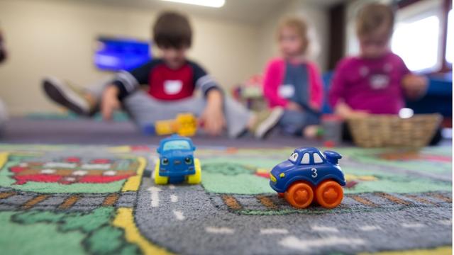 Three children playing with toy cars