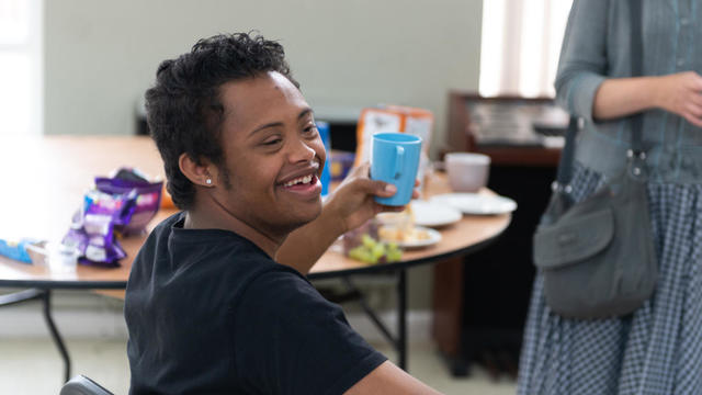 a young person holding a cup and smiling