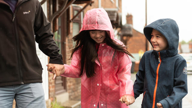 Family walking in the rain, girl smiling