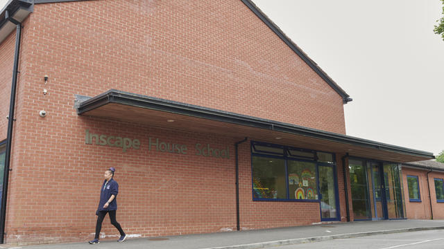 A photograph of the front of the Inscape school building with a member of staff walking in front