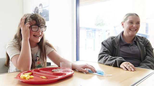 A Inscape student laughing with a member of staff whilst eating their lunch