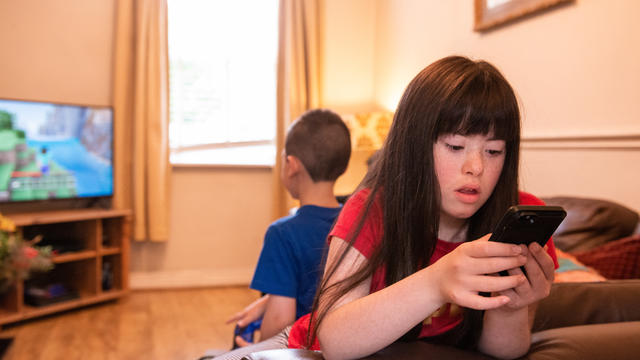 A girl in a red top looking at a mobile phone