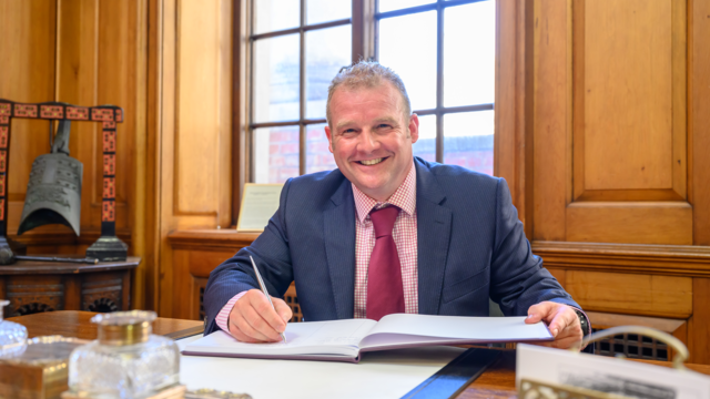 Photo of Giles Gaddum smiling at desk