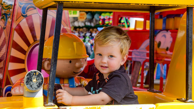 A child looking at the camera and enjoying one of the festival's rides.