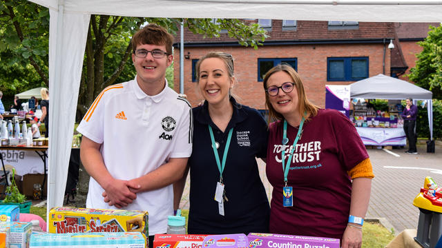 three people smiling stood at a stall