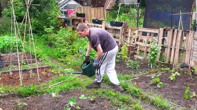 The young person's dad watering the garden