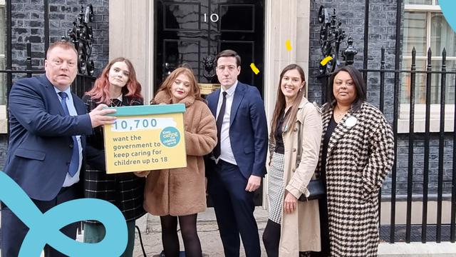 A group of young campaigners stand outside 10 Downing Street with a yellow box. It reads 10,800 people want the government to keep caring for children up to 18