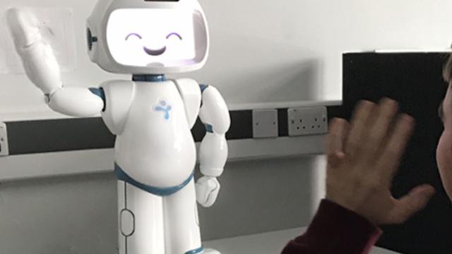 A robot waving with a person waving back at it