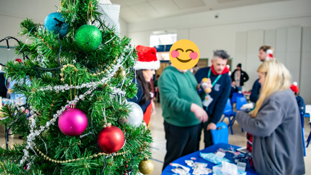 Decorated christmas tree in front of a booth with people getting temporary tattoos. 