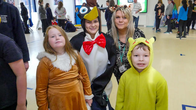 2 teachers and 2 children dressed up as animals: a penguin, a giraffe, Pikach