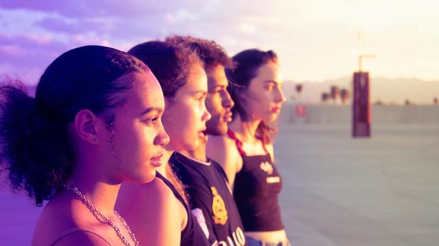 A photo of four teens stood in a row, looking out into the distance.