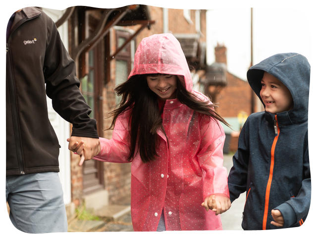 Family walking in the rain, girl smiling