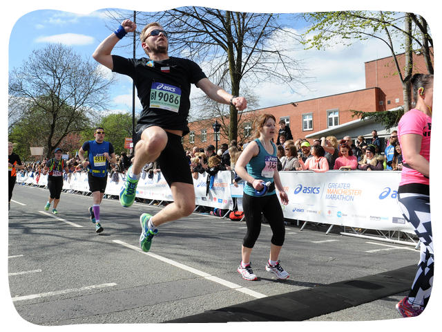 a man punching the air as he crosses the finish line of the Manchester Marathon