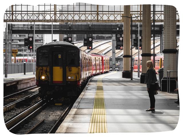 Person waiting behind the yellow line in on a train station platform. A train is approaching the platform. 